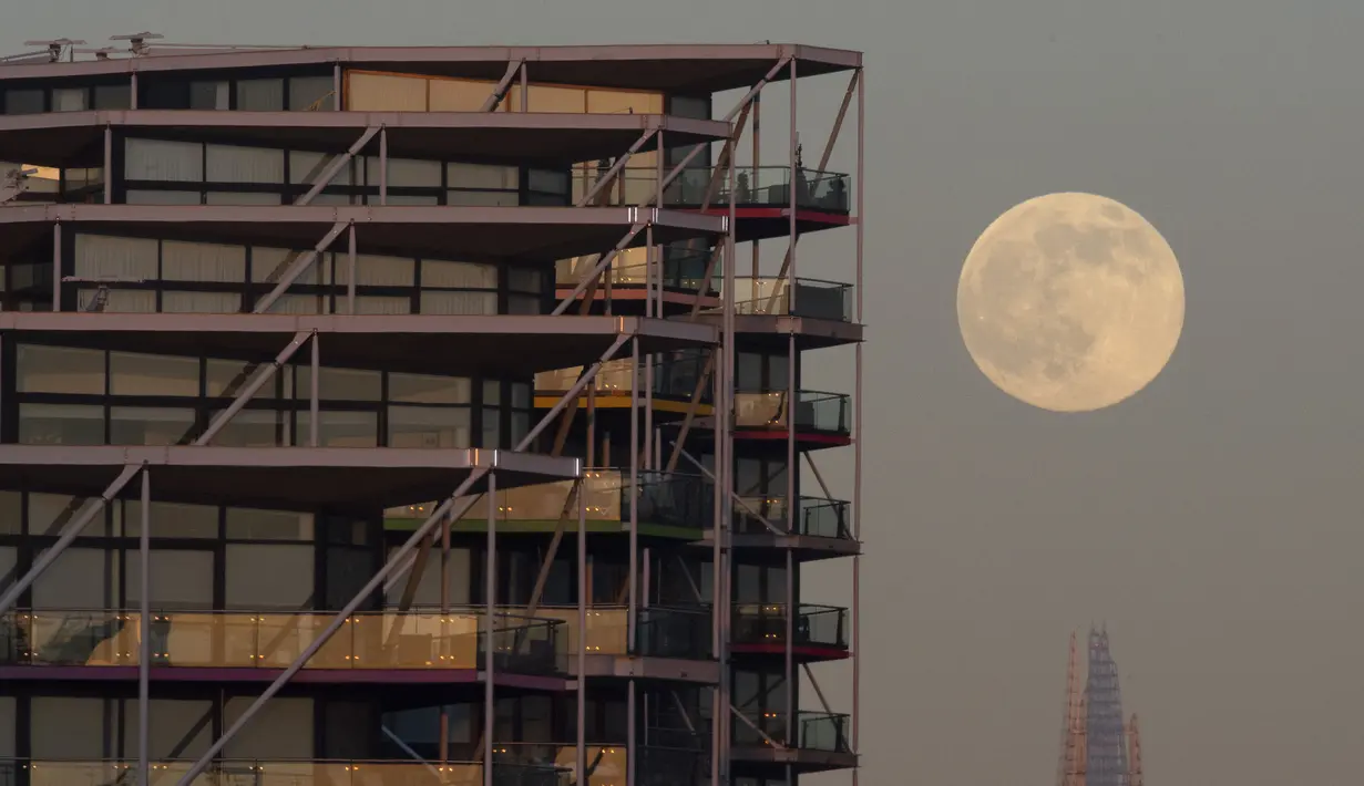 The Wolf Moon, bulan purnama pertama tahun ini, muncul di belakang The Shard di pusat kota London, Senin (17/1/2022). Wolf Moon atau disebut juga Bulan purnama Serigala adalah sebutan untuk bulan purnama pertama di Januari. (Justin TALLIS / AFP)