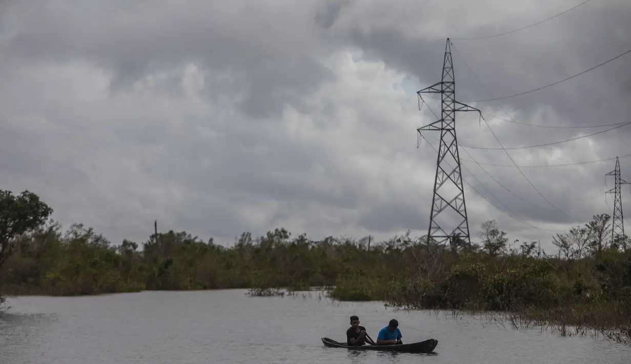 Warga menyeberangi banjir dengan sampan yang disebabkan oleh Boom Sungai Wawa setelah melintas Badai Iota di Bilwi, Puerto Cabezas, Nikaragua (18/11/2020). Badai Iota telah menewaskan sedikitnya sembilan orang saat menghancurkan rumah, menumbangkan pohon dan menggenangi air. (AFP/Inti Ocon)