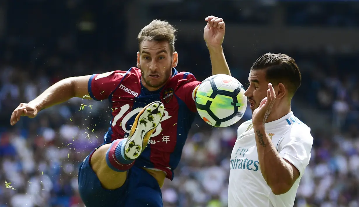 Pemain Levante, Ivan Lopez (kiri) menghalau bola dari kejaran pemain Real Madrid, Theo Hernandez pada lanjutan La Liga di Santiago Bernabeu stadium, Madrid (9/9/2017). Madrid bermain imbang 1-1. (AFP/Pierre-Philippe Marcou)
