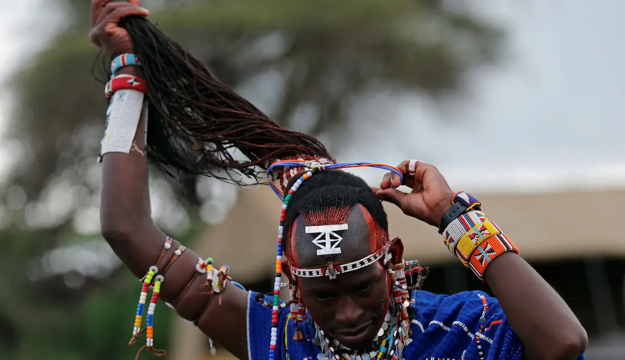Seorang suku Maasai mengikat rambutnya saat persiapan mengikuti Olimpiade Masai 2016 di dekat perbatasan Kenya-Tanzania (10/12). Suku Maasai adalah kelompok suku asli dari Afrika Timur yang memiliki pola hidup semi-nomaden. (Reuters/Thomas Mukoya)