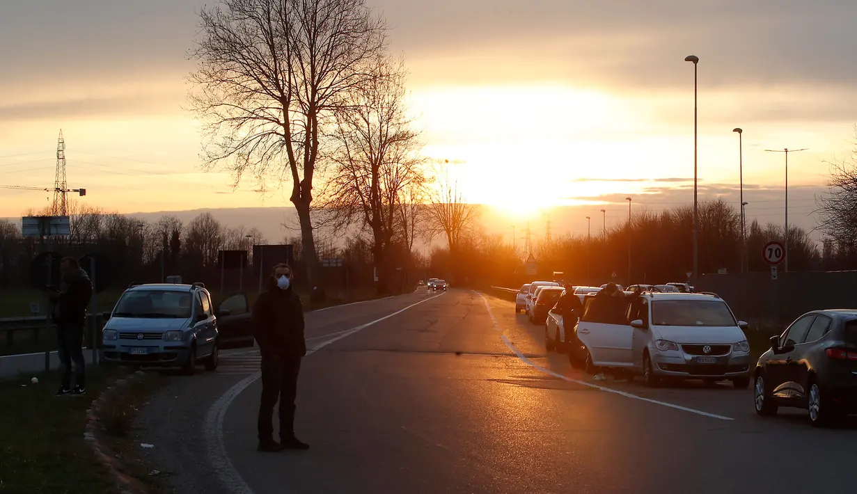 Orang-orang menunggu untuk dapat memasuki Kota Casalpusterlengo setelah pemerintah memperluas karantina di wilayah Lombardy, Italia, Minggu (8/3/2020). Penutupan seluruh wilayah Italia dilakukan setelah korban tewas akibat virus corona (COVID-19) terus meningkat. (AP Photo/Antonio Calanni)