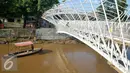 Perahu melintas di bawah Pembangunan jembatan penyeberangan orang (JPO) sungai Ciliwung, Jakarta, Senin (4/4). Rencaanya JPO tersebut siap digunakan pada 6 April mendatang. (Liputan6.com/Yoppy Renato)