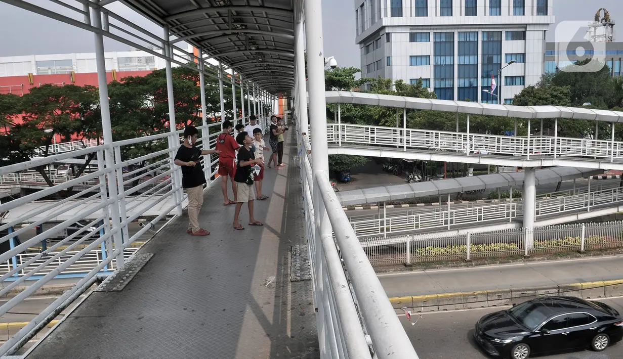 Sejumlah anak menerbangkan layangan dari Jembatan Penyeberangan Orang (JPO) di Jakarta, Kamis (11/6/2020). Minimnya ruang terbuka di sekitar tempat tinggal anak-anak itu menyebabkan mereka terpaksa bermain layang-layang di JPO yang sangat berisiko dan berbahaya. (merdeka.com/Iqbal Nugroho)
