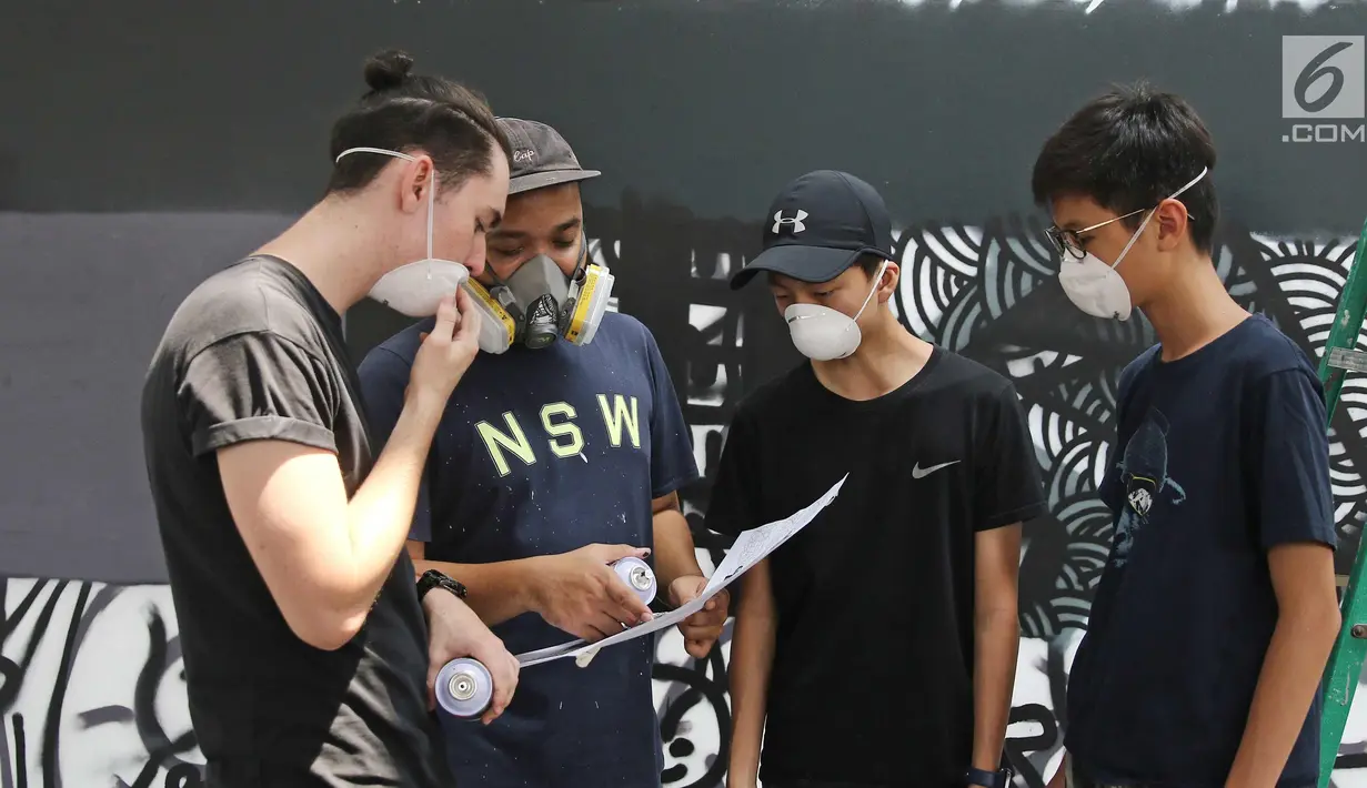 Siswa Menengah dan Menengah Atas Jakarta Intercultural School (JIS) dan Darbotz, seniman Mural Art kenamaan Indonesia (kedua kiri), tengah berdiskusi di workshop melukis mural di dinding sekolah, Jakarta, Sabtu (7/4). (Liputan6.com/Herman Zakharia)
