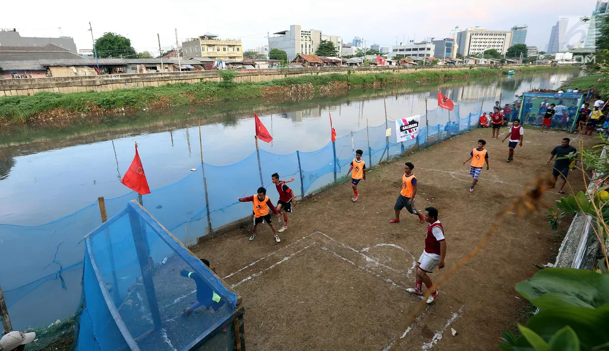 Warga bermain dalam kompetisi sepak bola di pinggir Kali Banjir Kanal Barat, Jakarta, Sabtu (5/11). Minimnya sarana bermain sepak bola mengakibatkan warga terpaksa memanfaatkan lahan di pinggir kali tersebut untuk bermain. (Liputan6.com/Johan Tallo)