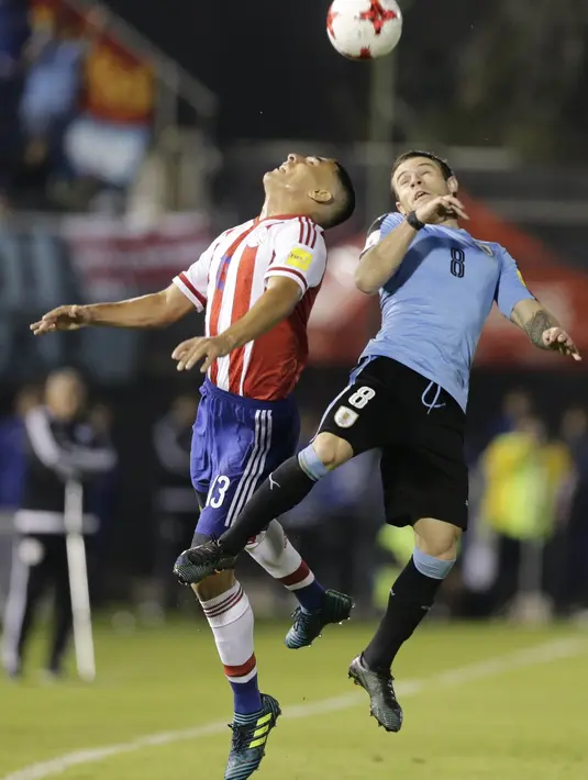 Gelandang Uruguay, Nahitan Nandez, berebut bola dengan bek Paraguay, Junior Alonso, pada laga kualifikasi piala dunia 2018 di Stadion Defensores del Chaco, Rabu (6/9/2017). Uruguay menang 2-1 atas Paraguay. (AP/Jorge Saenz)