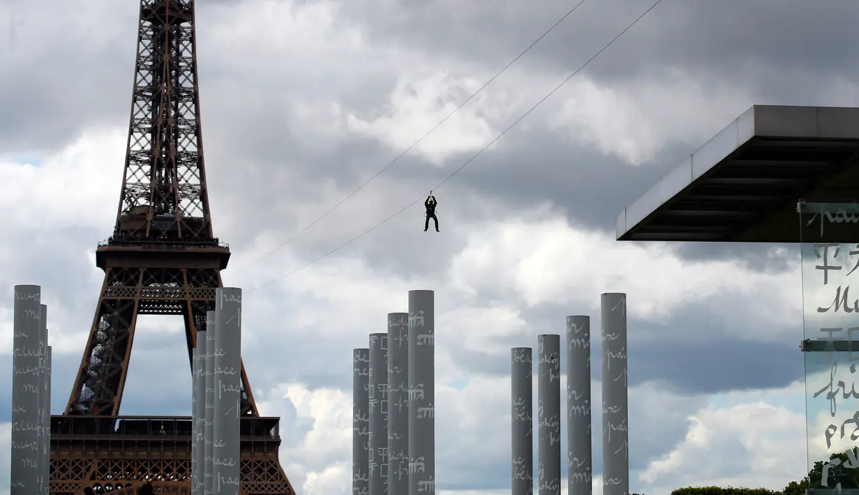 Pengunjung meluncur dengan seutas tali saat melakukan permainan Zip Line dari lantai dua Menara Eiffel di atas taman Champ de Mars, Paris, Selasa (28/5/2019). Permainan ini akan membiarkan pengunjung terbang di atas kerumunan turis di Champs de Mars sebelum mendarat dengan selamat (AP/Francois Mori)