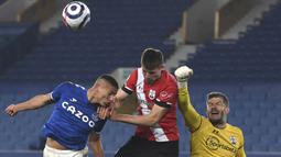 Kiper Southampton, Fraser Forster (kanan) meninju bola dari ancaman striker Everton, Richarlison (kiri) dalam laga lanjutan Liga Inggris 2020/21 pekan ke-26 di Goodison Park, Liverpool, Senin (1/3/2021). Southampton kalah 0-1 dari Everton. (AP/Gareth Copley/Pool)