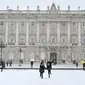 Dua gadis berlari melewati salju di luar Istana Kerajaan, Madrid, Spanyol, Jumat (8/1/2021). Salju tebal menutupi hingga setengah dari Spanyol dan menyebabkan penurunan suhu yang besar. (GABRIEL BOUYS/AFP)