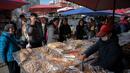 Sejumlah orang mengantre saat berbelanja kue di pasar di Beijing (20/11).  (AFP Photo/Nicolas Asfouri)