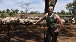 Emma Billet berpose dengan latar belakang kumpulan domba di tempat pemotong bulu domba di New South Wales, Australia (21/2). Dalam sehari Emma dapat mencukur bulu domba sebanyak 120 ekor. (AFP/Peter Parks)