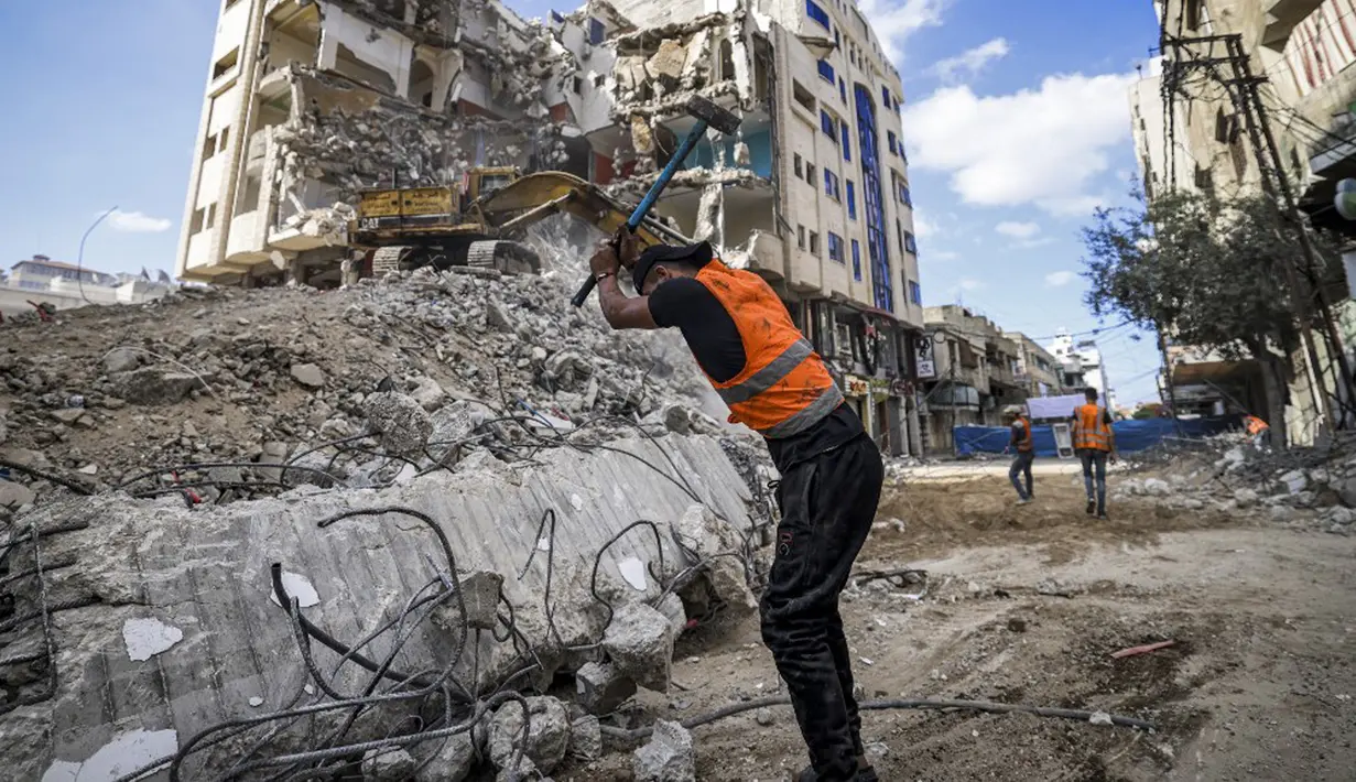 Seorang pekerja Palestina memecahkan puing-puing dari sebuah bangunan yang hancur selama konflik Mei 2021 antara Hamas dan Israel di Kota Gaza, Sabtu (5/6/2021). (MAHMUD HAMS/AFP)