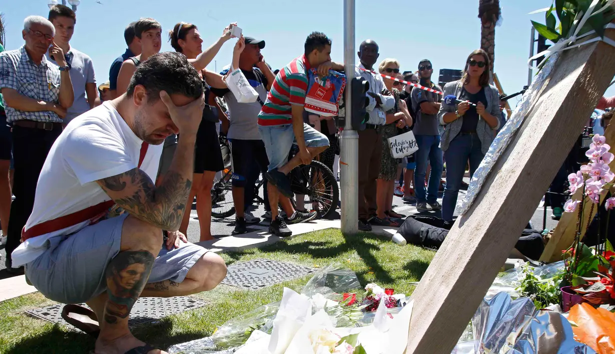 Seorang pria terlihat di dekat karangan bunga di tempat lokasi Teror Truk Maut Prancis saat merayakan hari Bastille di Nice, Prancis, (15/7). Sedikitnya 84 orang tewas dan ratusan lainnya luka akibat hantaman truk tersebut.  (REUTERS/Pascal Rossignol)