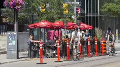 Pengendara sepeda melewati area makan terbuka sebuah restoran di Toronto, Kanada, 18 Juli 2020. Kota Toronto meluncurkan program CafeTO yang memungkinkan restoran dan bar memperluas area makan terbuka mereka guna melayani lebih banyak pelanggan dengan aman selama pandemi COVID-19. (Xinhua/Zou Zheng)