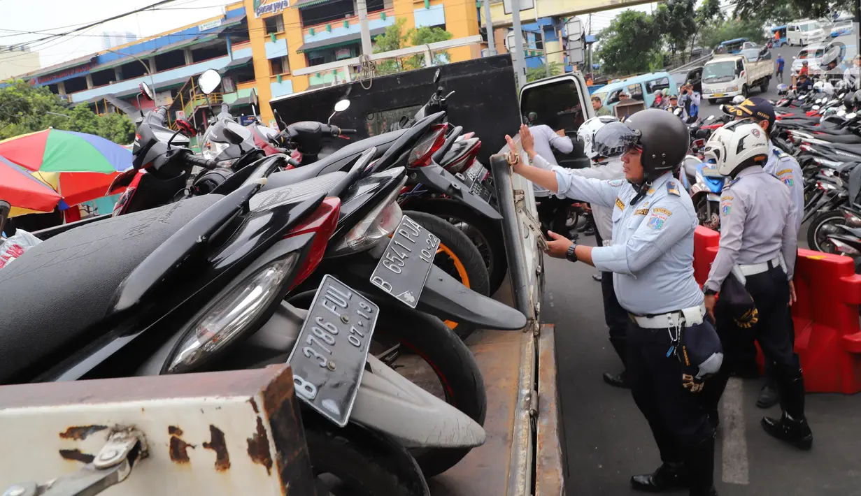 Petugas Dishub DKI mengangkut motor hasil razia parkir liar di kawasan Pasar Tanah Abang, Jakarta, Senin (21/5). Banyak preman yang memanfaatkan momen meningkatnya pengunjung pasar Tanah Abang dengan membuka area parkir liar. (Liputan6.com/Arya Manggala)