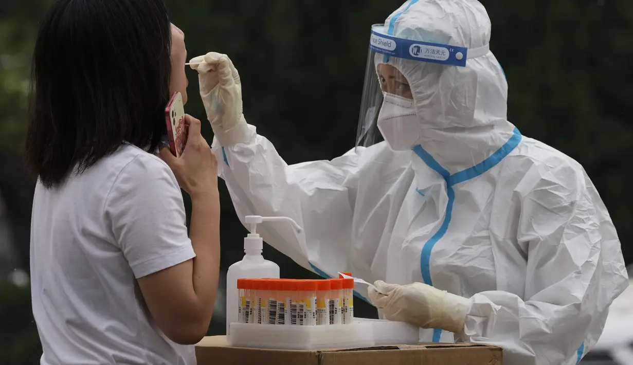 <p>Seorang pekerja medis mengambil sampel swab dari seorang warga selama pengujian massal untuk COVID-19 di distrik Chaoyang, Bejing, Senin (25/4/2022). Ibu kota China, Beijing, mulai menguji jutaan penduduk dan menutup kawasan perumahan dan bisnis pada Senin di tengah wabah baru COVID-19. (AP Photo/Ng Han Guan)</p>