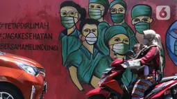 Pengedara motor melintas di depan mural tentang pandemi virus COVID-19 di Jalan Raya Jakarta-Bogor, Depok, Jawa Barat, Selasa (7/4/2020). Mural tersebut sebagai bentuk dukungan kepada tenaga medis yang menjadi garda terdepan menghadapi COVID-19 di Indonesia. (Liputan6.com/Helmi Fithriansyah)