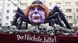 Sebuah kereta karnaval membawa karikatur yang menggambarkan kanselir Jerman, Angela Merkel sebagai Black Widow dengan tulisan "Yang berikutnya, tolong!" dalam parade karnaval Rose Monday di Mainz, Jerman barat, Senin (12/2). (Patrik STOLLARZ/AFP)
