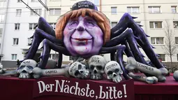 Sebuah kereta karnaval membawa karikatur yang menggambarkan kanselir Jerman, Angela Merkel sebagai Black Widow dengan tulisan "Yang berikutnya, tolong!" dalam parade karnaval Rose Monday di Mainz, Jerman barat, Senin (12/2). (Patrik STOLLARZ/AFP)