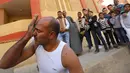 Karim Hussein memasukkan pecahan kaca ke dalam matanya saat unjuk kebolehan di Kairo (18/3/2016). Warga sekitar tampak menonton aksi mengerikan dari Karim Hussein "The Pharaoh"  (Reuters/ Mohamed Abd El Ghany)