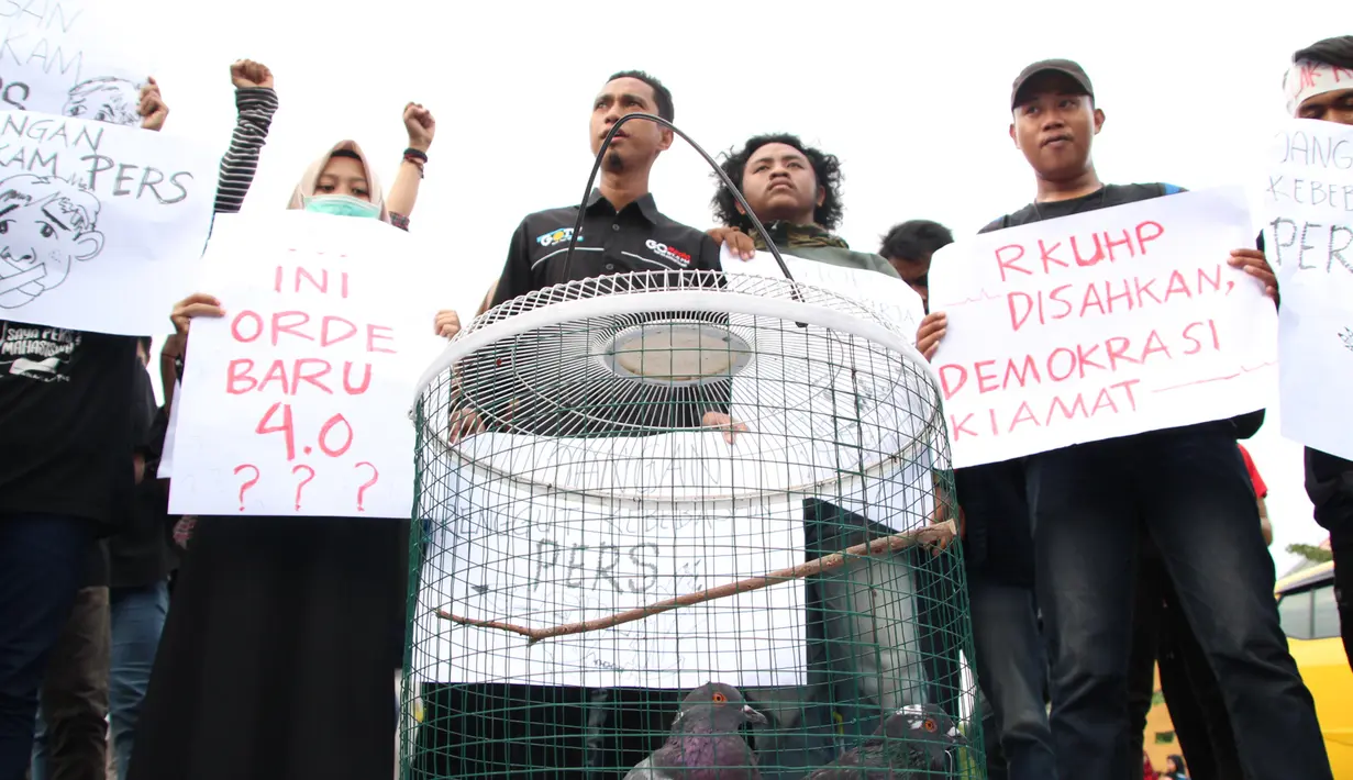 Massa yang tergabung dalam Aliansi Jurnalis Gorontalo membawa sejumlah poster saat menggelar aksi menolak RUU KUHP di Gorontalo, Senin (23/9/2019). Dalam aksinya massa bergerak dari Bundaran Saronde Gorontalo menuju Gerbang Kampus Universitas Negeri Gorontalo (UNG). (Liputan6.com/Arfandi Ibrahim)