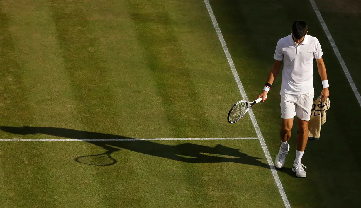 Petenis Serbia, Novak Djokovic berjalan di lapangan pada babak perempatfinal Wimbledon 2017 saat bertemu petenis Ceko, Tomas Berdych, Rabu (12/7). Djokovic memutuskan mundur setelah mengalami cedera siku saat menjalani pertandingan. (AP/Alastair Grant)