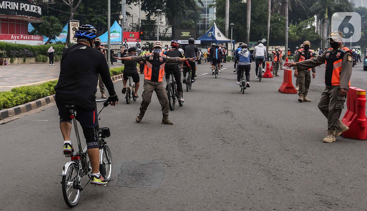 Satpol PP menghentikan pesepeda yang tidak mengenakan masker dengan benar di kawasan Bundaran HI, Jakarta, Minggu (17/1/2021). Pemerintah terus melakukan berbagai upaya guna mencegah penyebaran COVID-19 dan menurunkan angka masyarakat yang terpapar virus corona. (Liputan6.com/Johan Tallo)