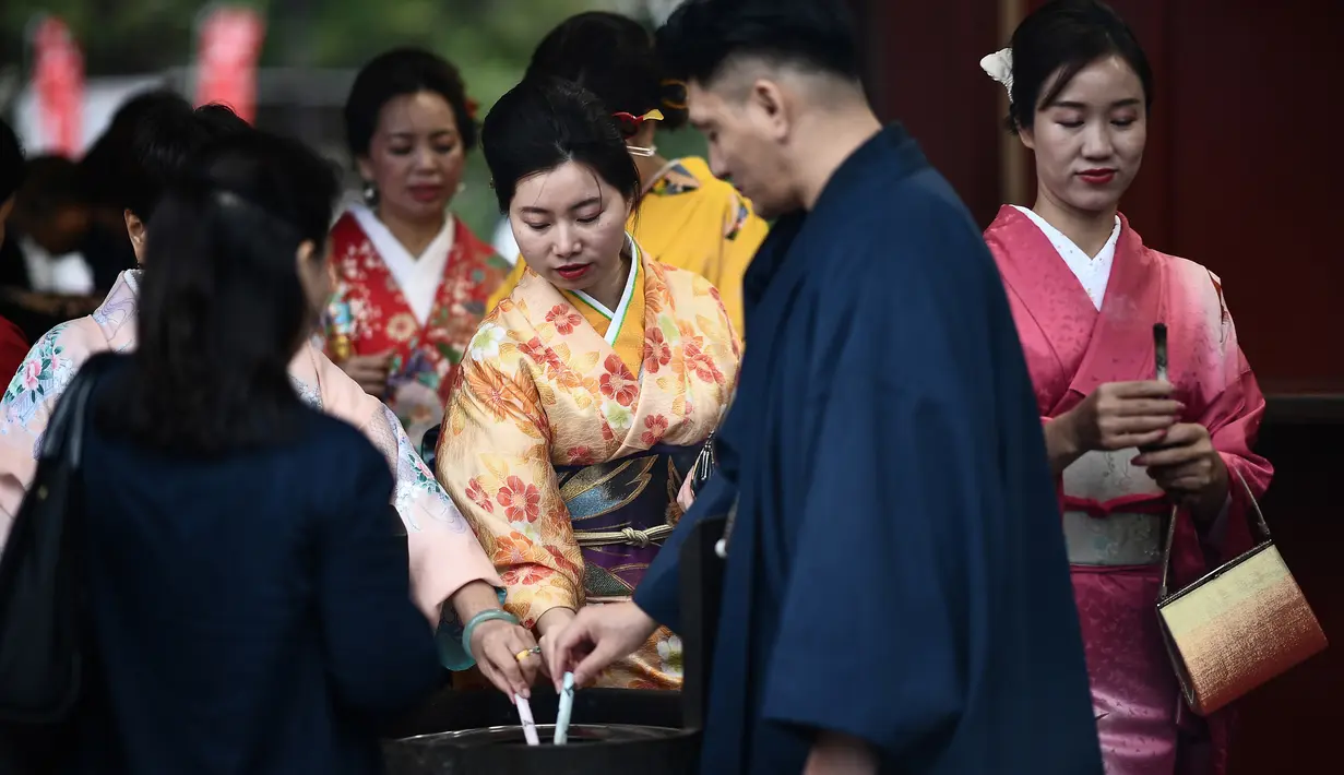 Gambar pada 21 Oktober 2019 menunjukkan wisatawan mengenakan pakaian tradisional Jepang mengunjungi kuil Senso-ji di Tokyo. Sensoji Temple merupakan salah satu kuil tertua di Jepang yang terletak di Asakusa. (Anne-Christine POUJOULAT / AFP)