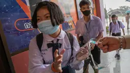 Guru memberikan pelindung wajah kepada seorang siswa di Samkhok School di Pathum Thani, Bangkok, Rabu (1/7/2020). Thailand telah memulai fase kelima relaksasi pembatasan covid-19 yang memungkinkan kembali dibukanya sekolah-sekolah setelah ditutup sejak Maret lalu. (AP/Sakchai Lalit)
