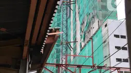 Kereta commuterline melintas dekat proyek pembangunan Apartemen Mahata Tanjung Barat di sekitar Stasiun Tanjung Barat, Jakarta, Kamis (30/1/2020). Apartemen Mahata Tanjung Barat dibangun di atas lahan seluas 15.244 meter persegi dan akan memiliki hunian sebanyak 1.216 unit. (Liputan6.com/Immanuel An