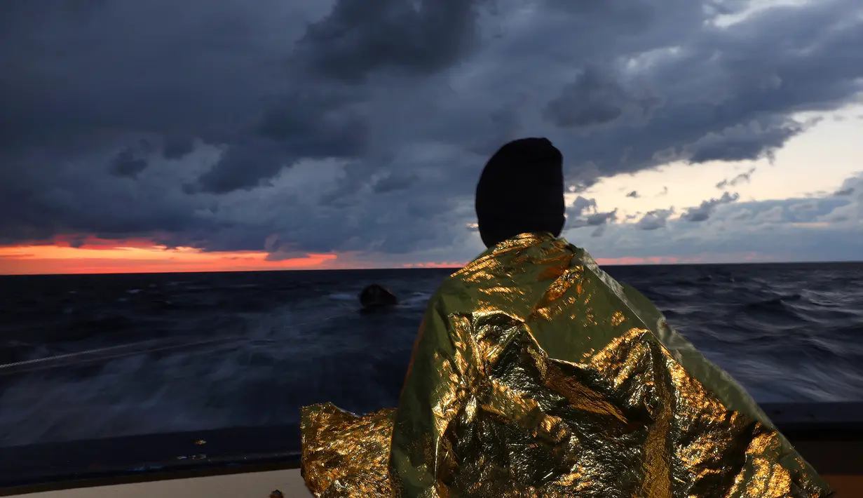 Imigran Afrika memakai selimut thermal usai diselamatkan di Laut Mediterania, sekitar 36 mil laut dari lepas pantai Libya (2/2). Penyelamatan yang dilakukan penjaga pantai Spanyol LSM Proactiva Open Arms ini sudah yang ke-112. (Reuters/Yannis Behrakis)