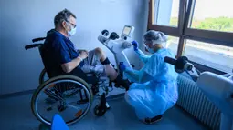 Fisioterapis merawat pasien yang sedang menjalani proses rehabilitasi setelah sembuh dari infeksi virus corona COVID-19 di sebuah rumah sakit di Illkirch-Graffenstaden, Prancis, Selasa (14/4/2020). Prancis memperpanjang lockdown hingga 11 Mei 2020. (PATRICK HERTZOG/AFP)