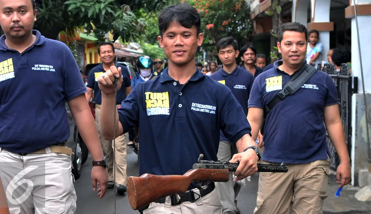 Petugas Polisi menyita senjata tajam dan senapan yang diduga digunakan oleh pelaku pengeroyokan, Jakarta, Kamis (21/1). Aparat gabungan lakukan penggeledahan dan mencari pelaku tersangka pengeroyokan di kampung Berlan. (Liputan6.com/Yoppy Renato)