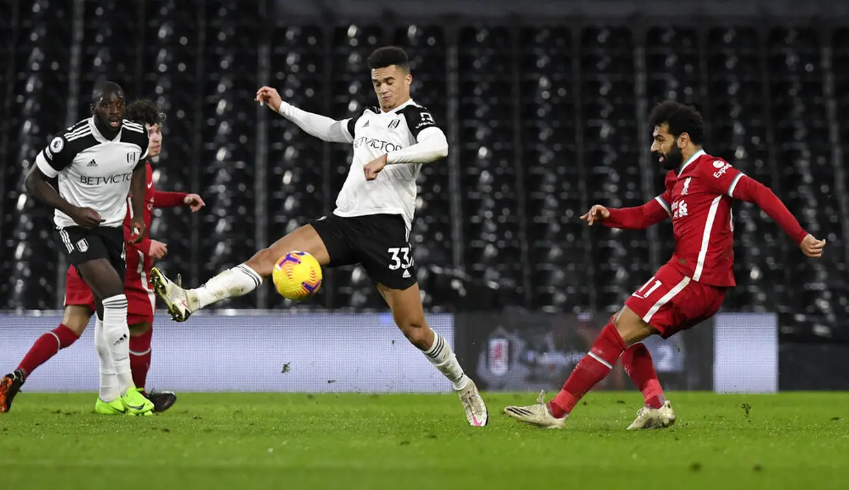 Pemain Fulham Antonee Robinson mencoba memblokir tembakan dari pemain Liverpool Mohamed Salah (kanan) pada pertandingan Liga Premier Inggris di Stadion Craven Cottage, London, Minggu (13/12/2020). Liverpool dan Fulham bermain imbang 1-1. (Neil Hall/Pool via AP)
