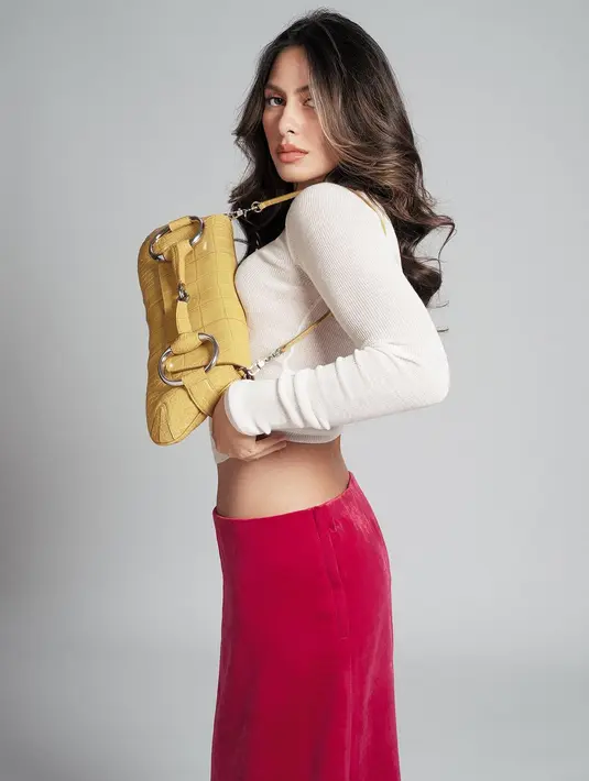 Valerie Thomas memesona dengan atasan lengan panjang berwarna putih, dipadu dengan rok merah muda dan menenteng tas berwarna kuning terang. [Foto: Instagram/winstongomez]