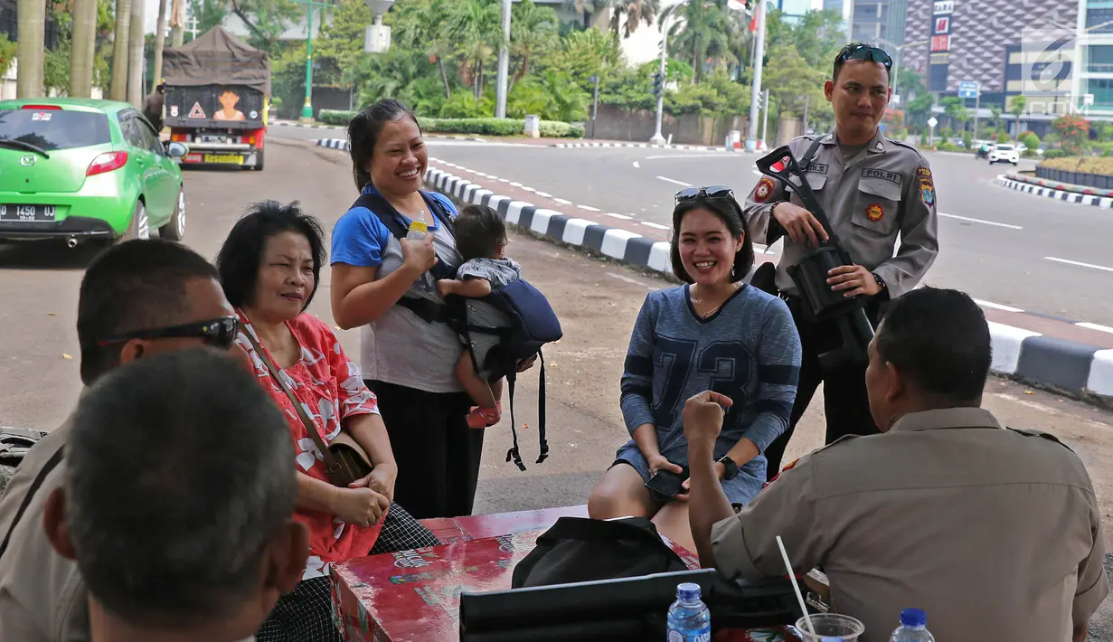 Sejumlah personel kepolisian berbincang saat melakukan penjagaan di kawasan Bundaran HI, Jakarta, Minggu (9/6/2019). Tidak sedikit aparat kepolisian terpaksa melewatkan Lebaran 2019 jauh dengan keluarga demi menjalankan tugas negara. (Liputan6.com/Herman Zakharia)