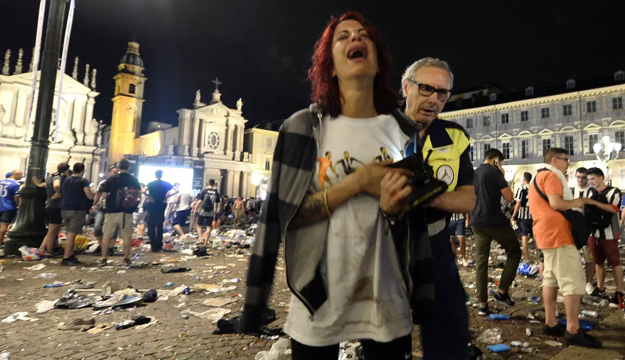 Seorang wanita menangis usai terjadi ledakan saat nonton bareng final Liga Champions di Piazza San Carlo, Turin, Sabtu (3/6/2017). Acara nobar dipadati sekitar 20.000 supporter Juventus. (AFP/Massimo Pinca)