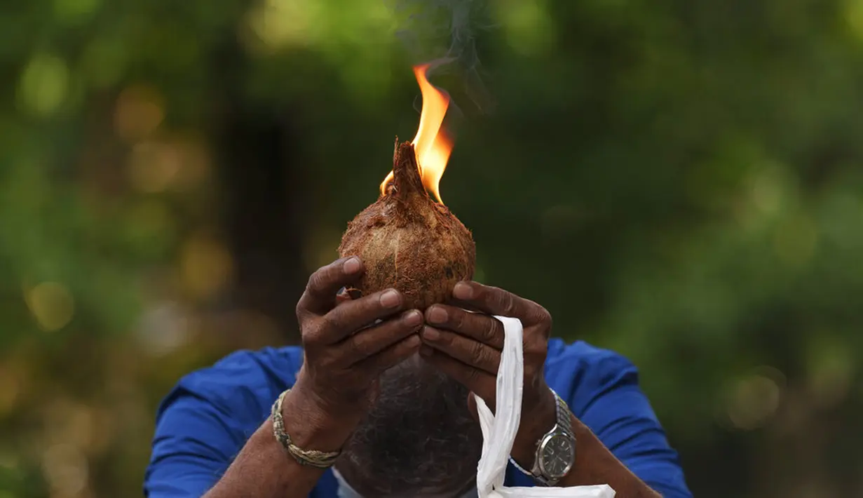 Seorang pria berdoa dengan kelapa menyala sebagai persembahan selama Festival Diwali di luar Kuil Batu Caves, Kuala Lumpur, Malaysia, Kamis (4/11/2021). Diwali adalah salah satu festival terpenting dalam agama Hindu, didedikasikan untuk penyembahan dewi kekayaan Lakshmi. (AP Photo/Vincent Thian)
