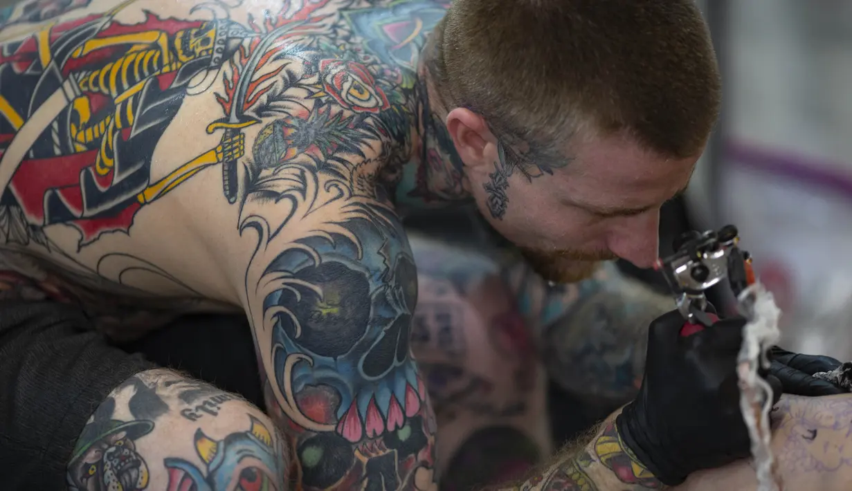 Seniman membuat tato pada tubuh seseorang dalam acara Sao Paulo Tattoo Week, Brasil, Jumat (25/10/2019). (AP Photo/Andre Penner)
