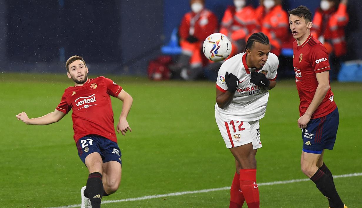 Gelandang Osasuna, Jon Moncayola (kiri) melepaskan tendangan yang berusaha diblok bek Sevilla, Jules Kounde dalam laga lanjutan Liga Spanyol 2020/21 pekan ke-24 di El Sadar Stadium, Plampona, Senin (22/2/2021). Osasuna kalah 0-2 dari Sevilla. (AFP/Ander Gillenea)