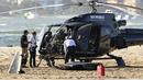 Petugas darurat memeriksa helikopter di lokasi tabrakan dekat Seaworld, di Gold Coast, Australia, Senin, 2 Januari 2023. Dua helikopter bertabrakan di udara menewaskan empat orang termasuk sepasang suami istri dari Inggris dalam kecelakaan yang menarik bantuan darurat dari pengunjung pantai selama musim panas. (Dave Hunt/AAP Image via AP)