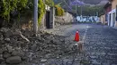 Batu memenuhi jalan setelah sebagian dinding rumah runtuh, dipicu oleh dipicu gempa bumi berkekuatan 6,2 skala Richter semalam di Antigua, Guatemala, 16 Februari 2022. Gempa tersebut menyebabkan tanah longsor di jalan, kerusakan rumah dan pemadaman listrik. (AP Photo/Santiago Billy)