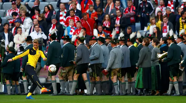 Pemain Borussia Dortmund Marco Reus melakukan pemanasan didekat  para pemusik Bavaria sebelum partai Bayern Munich dan Borussia Dortmund di Stadion Allianz Arena, Muenchen, Minggu (4/10/2015). (REUTERS/Michael Dalder)