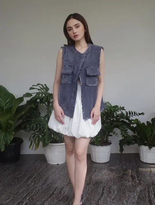 Syifa mengenakan long vest denim berkantong depan. Dipadukan mini skirt cloud putih dan heels hitam. [@syifahadju]