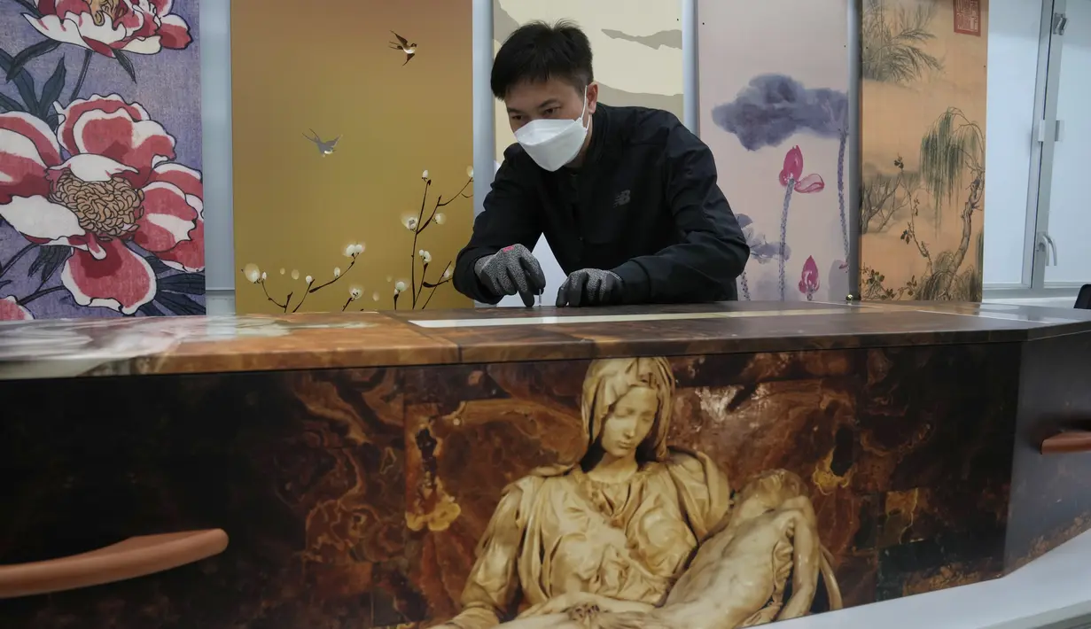 Seorang pekerja memperbaiki sekrup pada peti mati kertas di pabrik LifeArt di Hong Kong, Jumat, 18 Maret 2022. Hong Kong kekurangan peti mati selama wabah paling mematikan dari pandemi virus corona covid-19, yang telah menelan sekitar 6.000 nyawa sepanjang tahun ini. (AP Photo/Kin Cheung)
