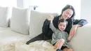 Brielle juga terlihat cantik dengan senyum tipis yang diumbarnya. Ia nampak kenakan mini dress abu-abu di pangkuan sang ibu [@julstelle]