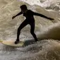 Peselancar berusaha berdiri di atas papan seluncur saat bermain "surfing" di sungai buatan Eisbach di English Garden Munich, Jerman pada 28 Mei 2019. Aliran air sungai Sungai Eisbach yang memiliki lebar 12 meter ini berasal dari Sungai Isar. (Photo by Peter Kneffel/dpa/AFP)