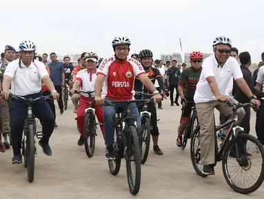 Gubernur DKI Jakarta Anies Baswedan bersepeda di kawasan Pantai Kita dan Pantai Maju, Minggu (23/12). Aksi itu mengawali Peletakkan Batu Pertama Jalur Jalan Sehat dan Sepeda Santai (Jalasena) di pulau reklamasi tersebut. (Liputan6.com/Herman Zakharia)