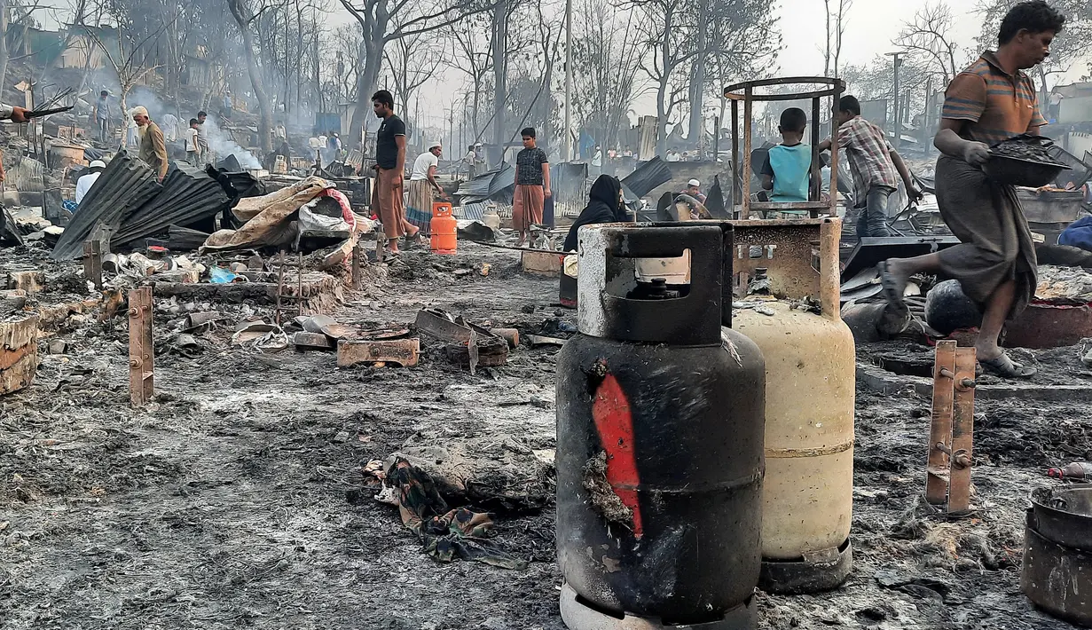Pengungsi Rohingya membersihkan puing-puing sisa kebakaran di kamp pengungsi di Balukhali, Bangladesh selatan (22/3/2021). Api menghancurkan ratusan tempat penampungan dan menyebabkan ribuan orang kehilangan tempat tinggal, kata pejabat dan saksi. (AFP Photo)