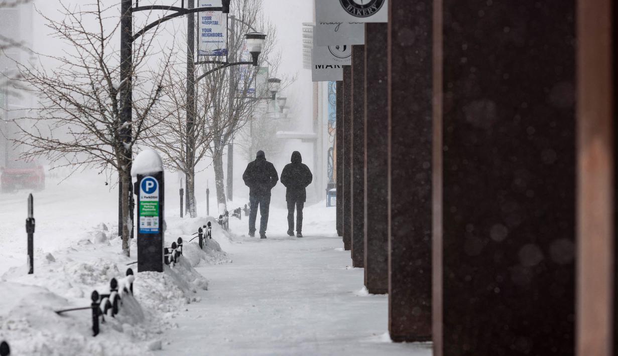 Orang-orang berjalan saat terjadi badai salju di lingkungan East Village, Des Moines, Iowa, pada tanggal 12 Januari 2024. (Christian MONTERROSA/AFP)